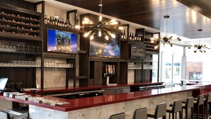 A modern bar area with a long counter, multiple TVs, and a variety of bottles and glasses. - Hilton Garden Inn Lehi (Lehi)