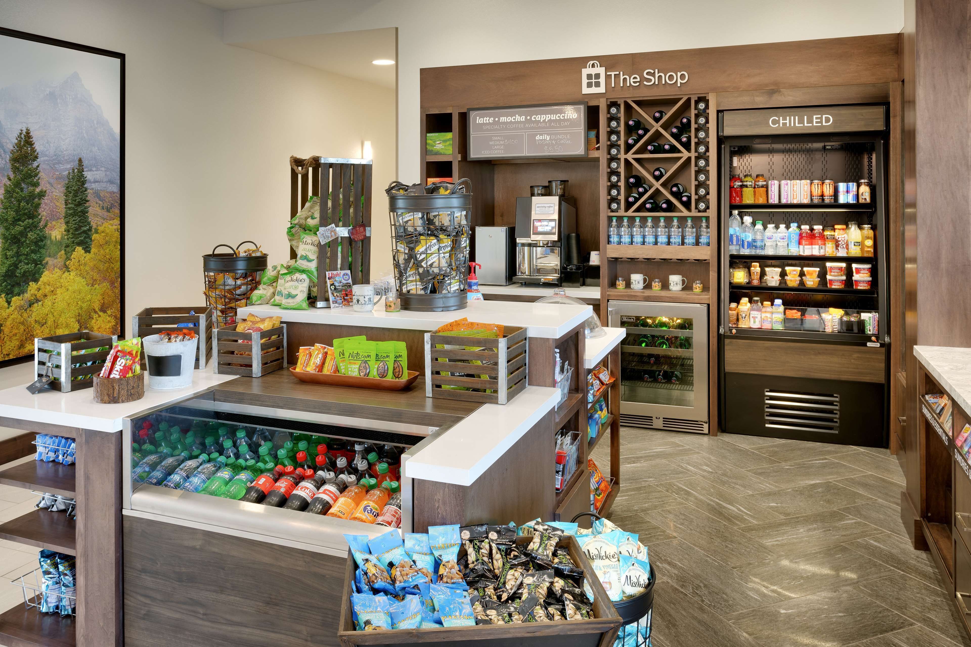 A coffee shop with a refrigerated section, a display of bottled water, and a variety of snacks.