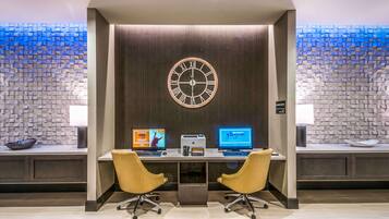 Un espacio de oficina moderno con dos escritorios, sillas, un reloj y una pared con textura.