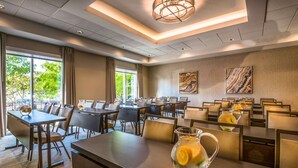 A hotel dining area with multiple tables and chairs, large windows with curtains, and a modern chandelier. - Hampton Inn & Suites Tallahassee Capitol - University (Tallahassee)