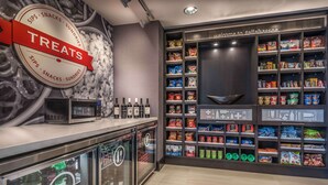 A modern snack and beverage area with a 'Treats' sign, refrigerated drinks, and a variety of snacks on shelves. - Hampton Inn & Suites Tallahassee Capitol - University (Tallahassee)