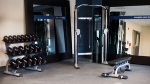 Una palestra con attrezzi per il sollevamento pesi, una panca e specchi.