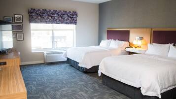 Une chambre d’hôtel avec deux lits, un bureau et une fenêtre donnant sur un paysage agréable.