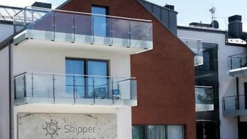 A modern hotel with a prominent 'Skipper' sign, a balcony, and potted plants in the foreground.