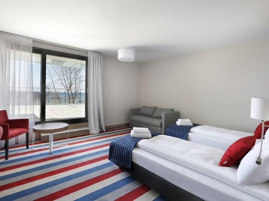 Une chambre d’hôtel avec une grande fenêtre, un canapé, un lit et une petite table.