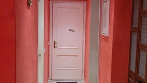 Un pasillo con paredes rojas, una puerta blanca y suelo de baldosas.