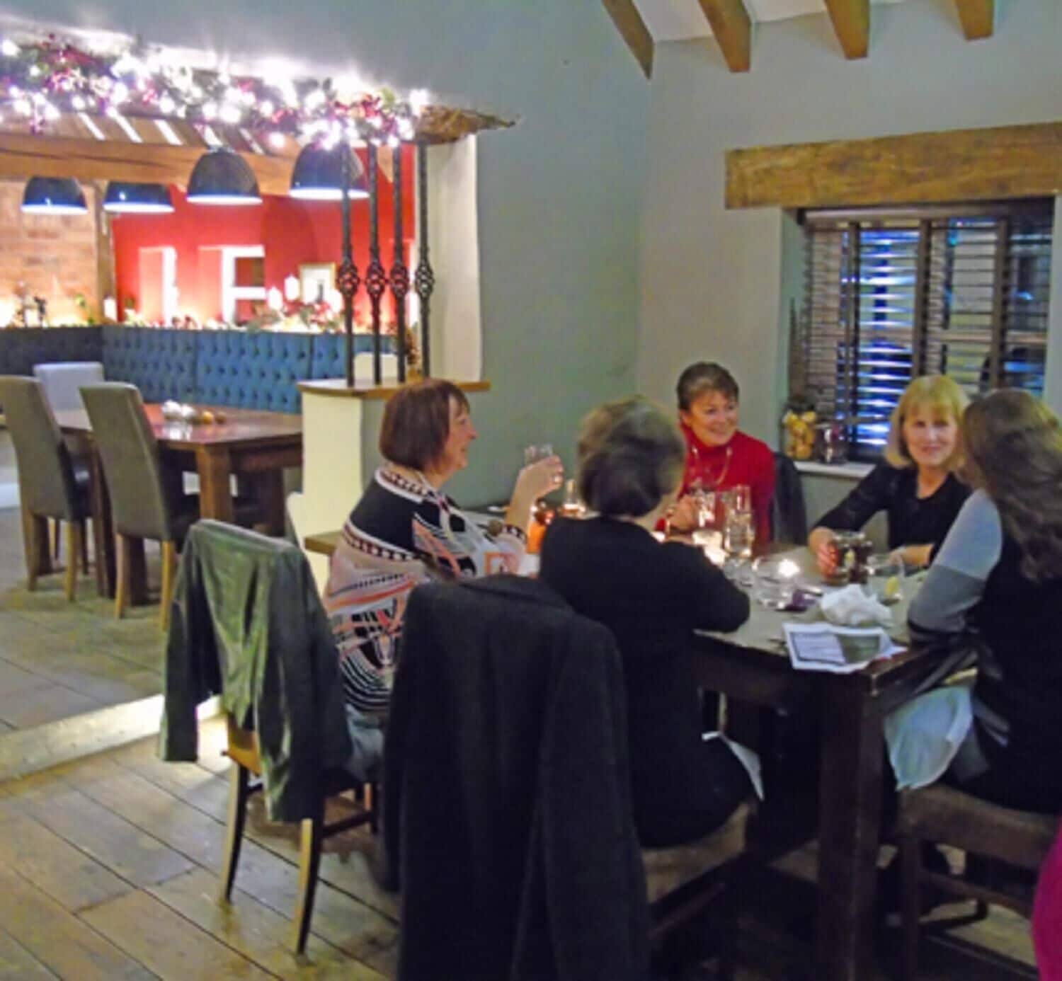 A group of people dining at a restaurant with a bar area in the background.