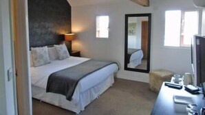 A bedroom with a bed, a desk, a chair, a lamp, and a mirror.