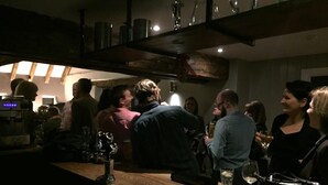 A bar area with wooden counters and hanging glasses.