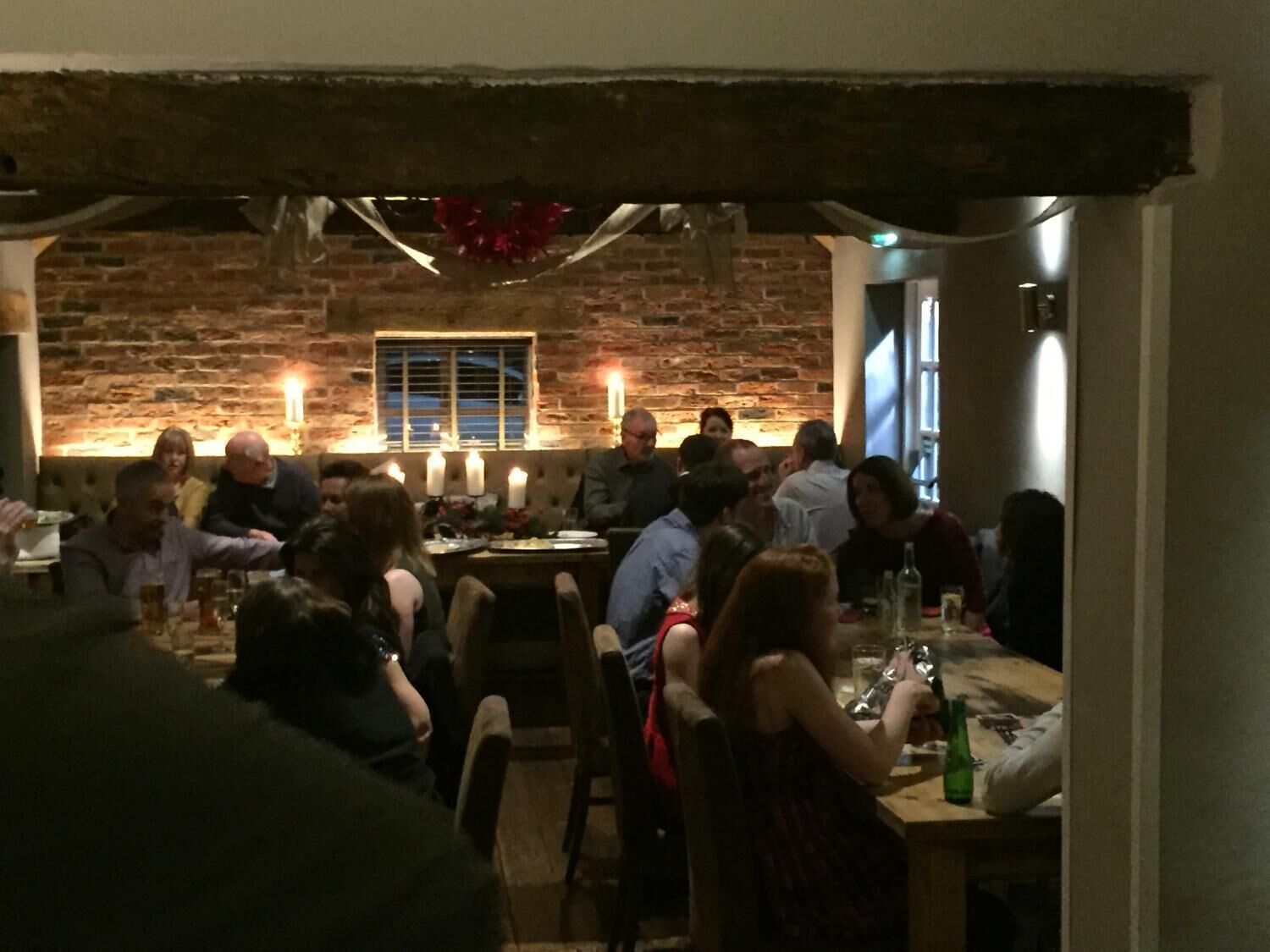 Un restaurant aux murs de briques, aux poutres apparentes et aux tables éclairées à la bougie.