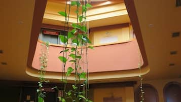 Un vestíbulo con una planta central, tragaluces y un cartel que dice "ASCENSOR PLANTA 2".