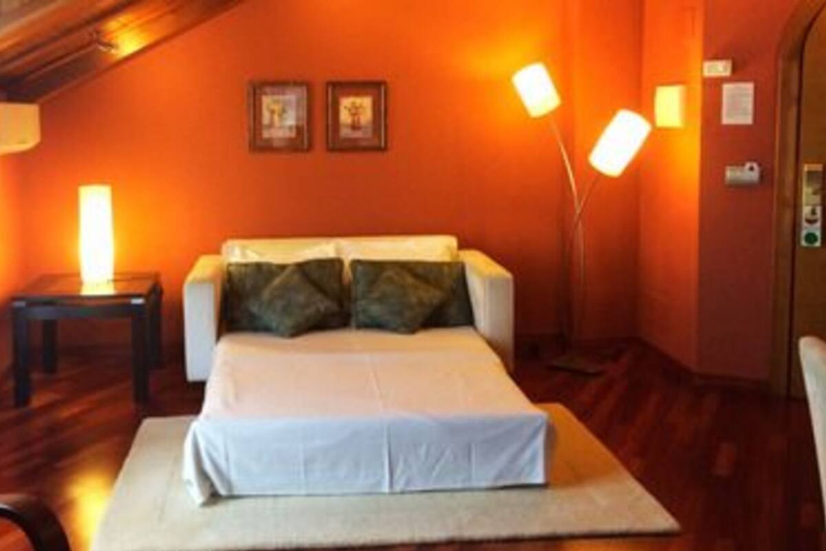 A room with a bed, a nightstand, a lamp, and a wall-mounted light fixture.