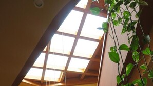 A multi-level atrium with a skylight, wooden beams, and hanging plants. - Hotel Las Eras (Zafra)