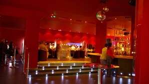 A bar area with a stage, seating, and a bar counter. - Hotel Las Eras (Zafra)