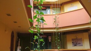 A multi-level interior with a central atrium, wooden flooring, and a hanging plant. - Hotel Las Eras (Zafra)