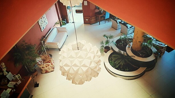 A spacious lobby with a white sofa, a coffee table, and a large decorative plant arrangement. - Hotel Las Eras (Zafra)