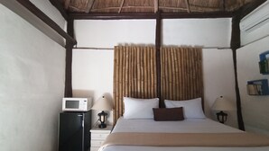 A bedroom with a bed, bedside tables, a microwave, lamps, and a bamboo curtain. - Nativ Tulum Hotel Boutique (Tulum)