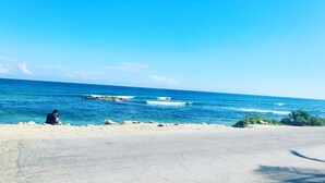 A coastal road with a person sitting on the beach, overlooking the ocean. - Nativ Tulum Hotel Boutique (Tulum)