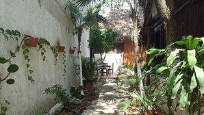 A narrow pathway flanked by potted plants and a rustic building with a thatched roof. - Nativ Tulum Hotel Boutique (Tulum)