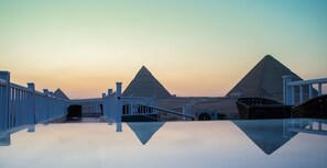 A reflective pool with a view of pyramids and a white fence.