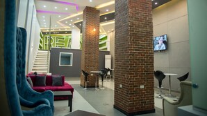 A modern lobby with a red sofa, black chairs, and a TV screen. - Marvel Stone Hotel (Giza)