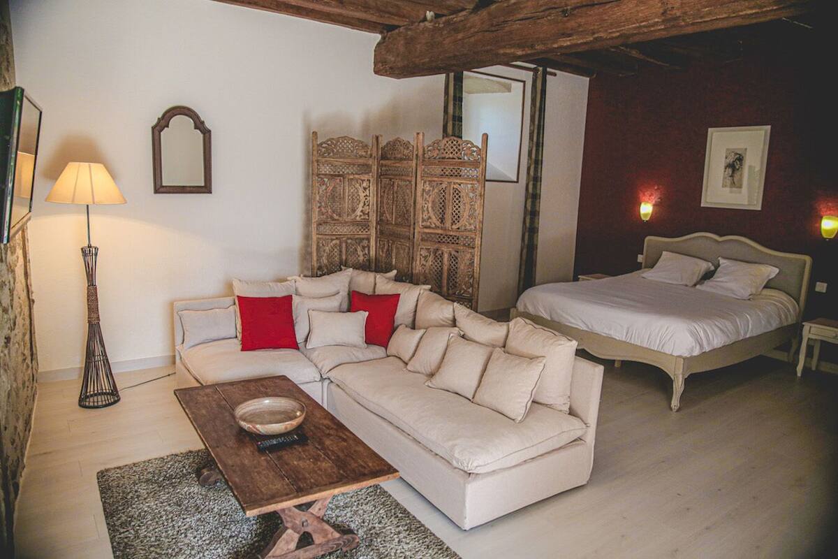 A cozy room with a sofa, a bed, a wooden coffee table, a lamp, and a decorative screen.