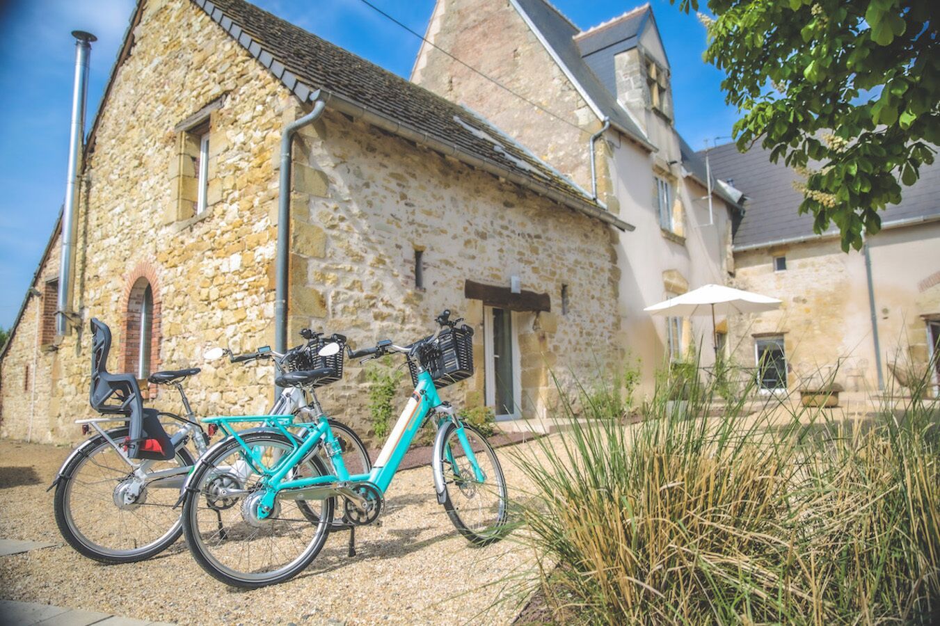 A stone building with a door and windows, a bicycle parked in front, and a white umbrella.
