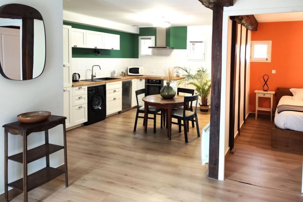 A compact kitchen with white cabinets, a wooden dining table, and a small dining area.