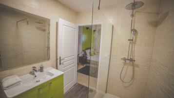 A modern bathroom with a glass-enclosed shower, a white sink, and a green vanity.