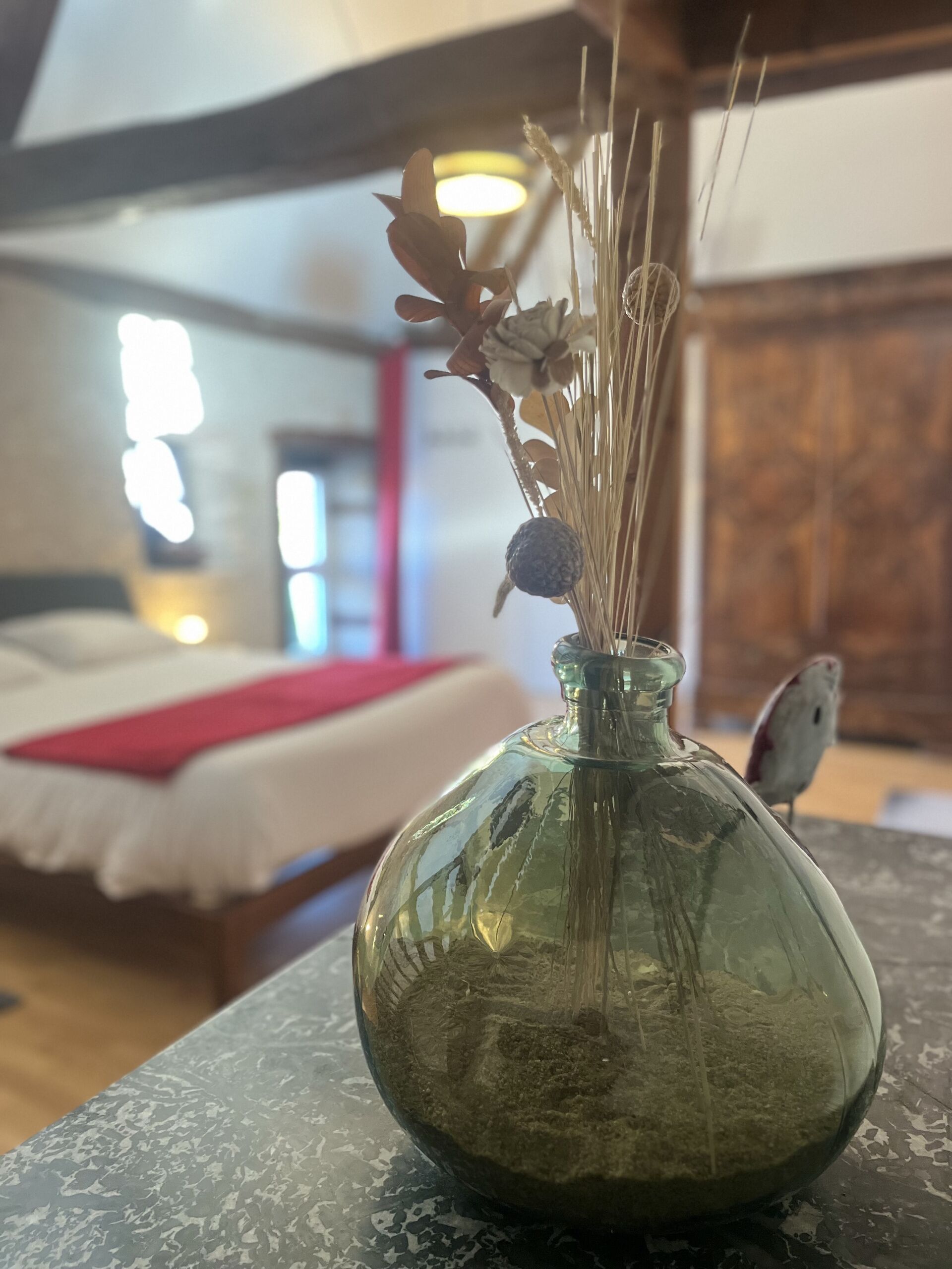 Een kamer met een bed, een tafel met een vaas en een vogel.