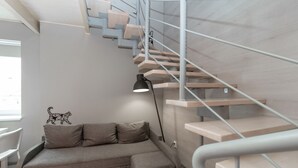 Ein modernes Interieur mit einer Holztreppe, einem grauen Sofa und einer Wandleuchte.