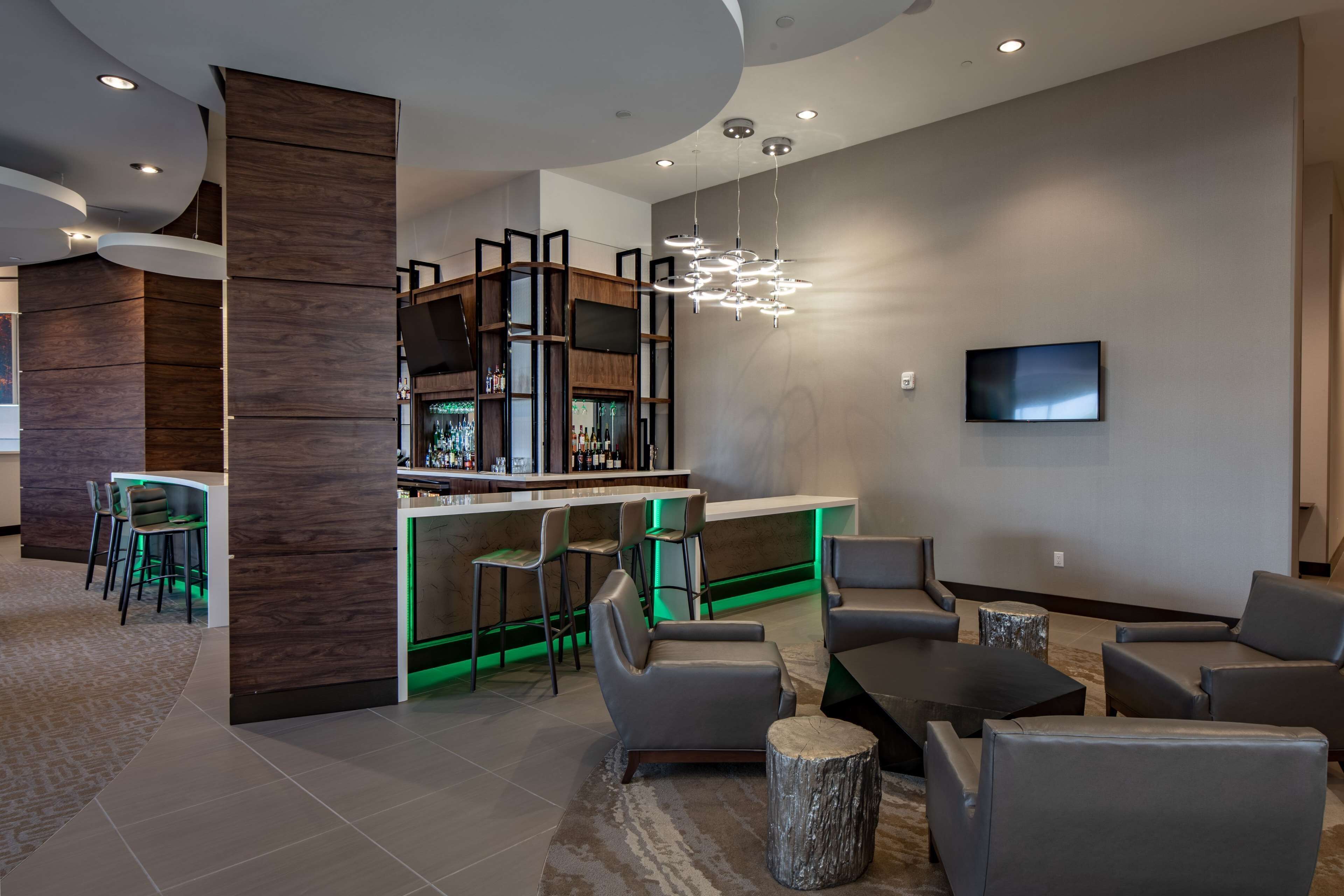 A modern bar area with a high counter, bar stools, and a television mounted on the wall.