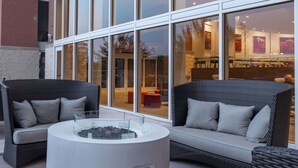 Un área de estar al aire libre con muebles de mimbre y una chimenea central.