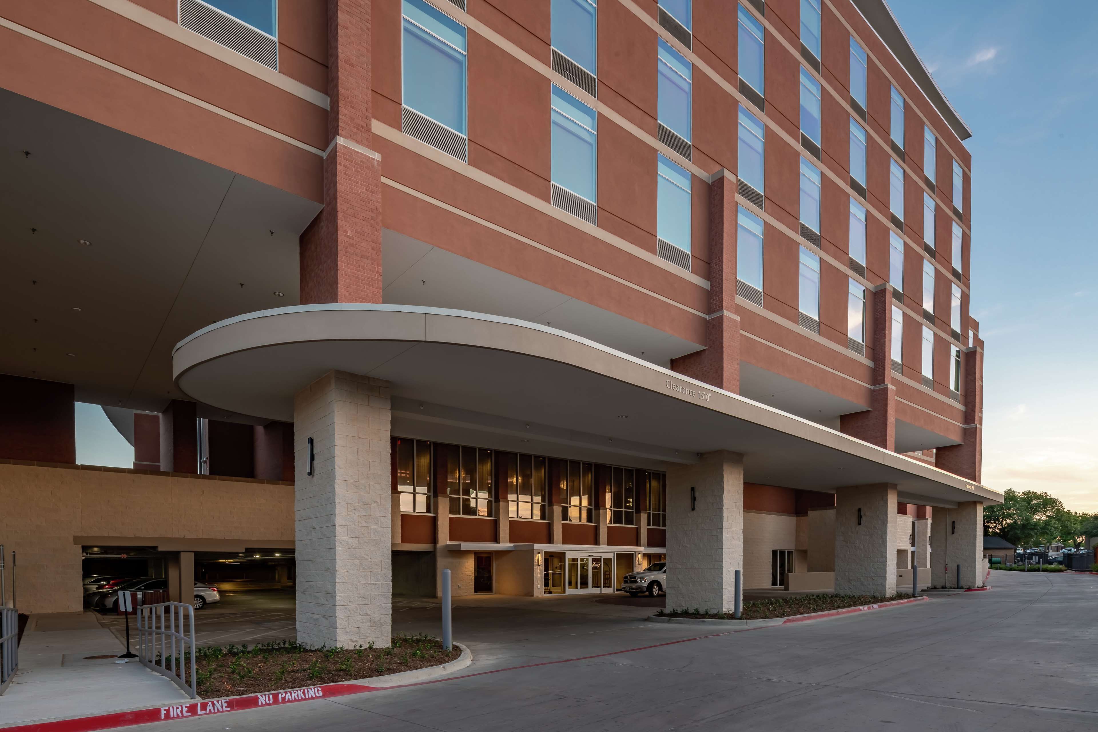 A multi-story hotel with a curved entrance canopy, a fire lane, and a parking area.