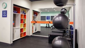 A gym with exercise equipment, a mirrored wall, and a storage area with colorful shelves. - Tru by Hilton Farmville (Farmville)