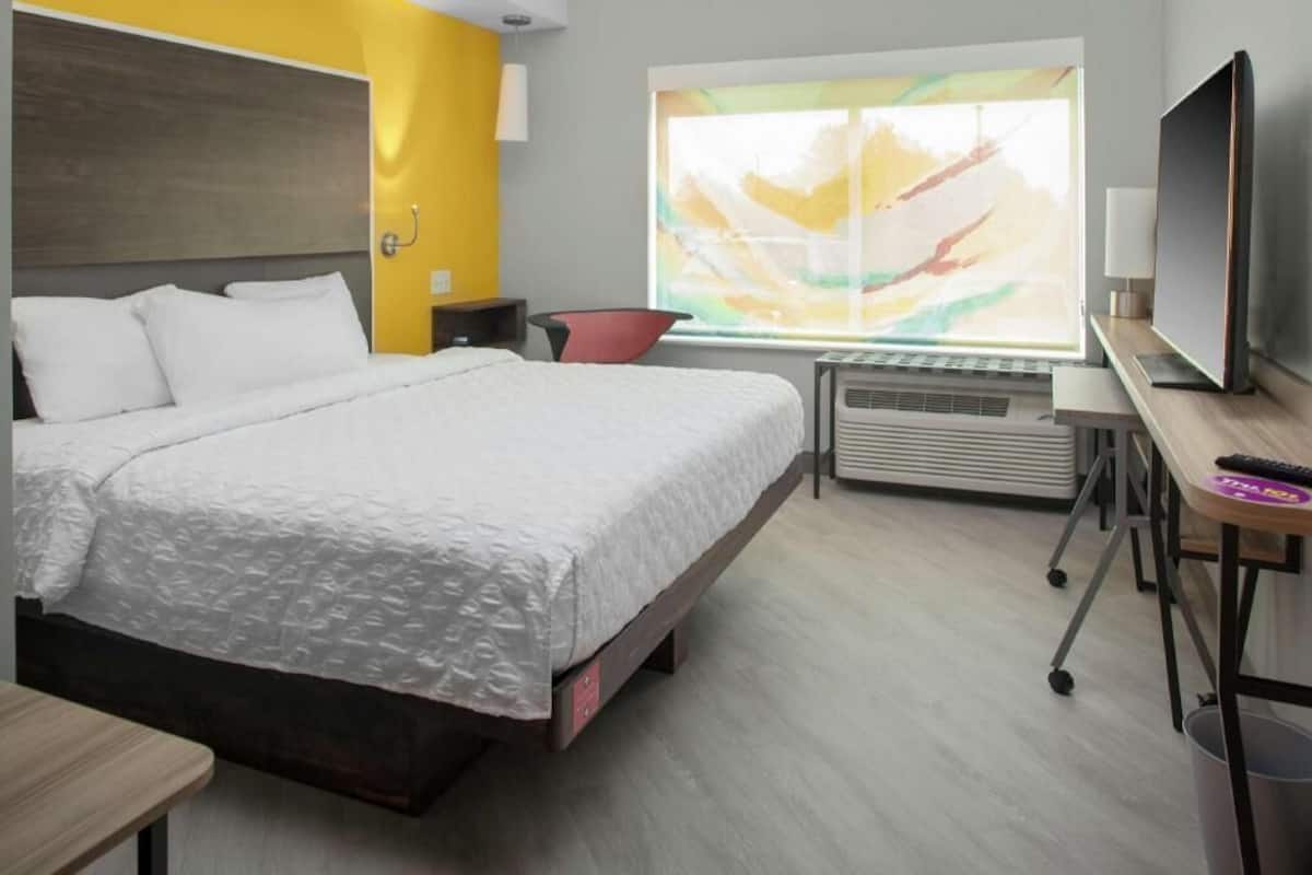 A hotel room with a bed, a desk, a television, and a window with a view.