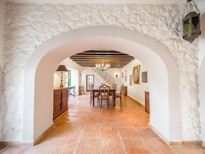 A spacious hallway with a tiled floor, a wooden dining table with chairs, and a staircase leading to another level.