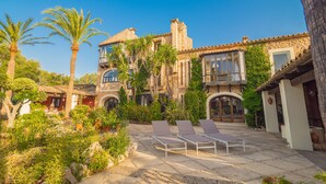 A Mediterranean-style villa with a courtyard, palm trees, and a pool area with sun loungers. - Villa Portol (Marratxi)