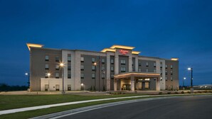 Un hôtel Hampton Inn au design moderne, caractérisé par un toit plat, une entrée centrale et une façade bien éclairée.