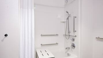 Un baño moderno con cabina de ducha, barras de apoyo y un lavamanos blanco.