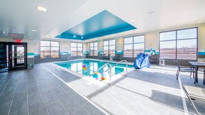 Une grande piscine intérieure avec des parois en verre transparent, un plafond bleu et une vue sur l’extérieur.