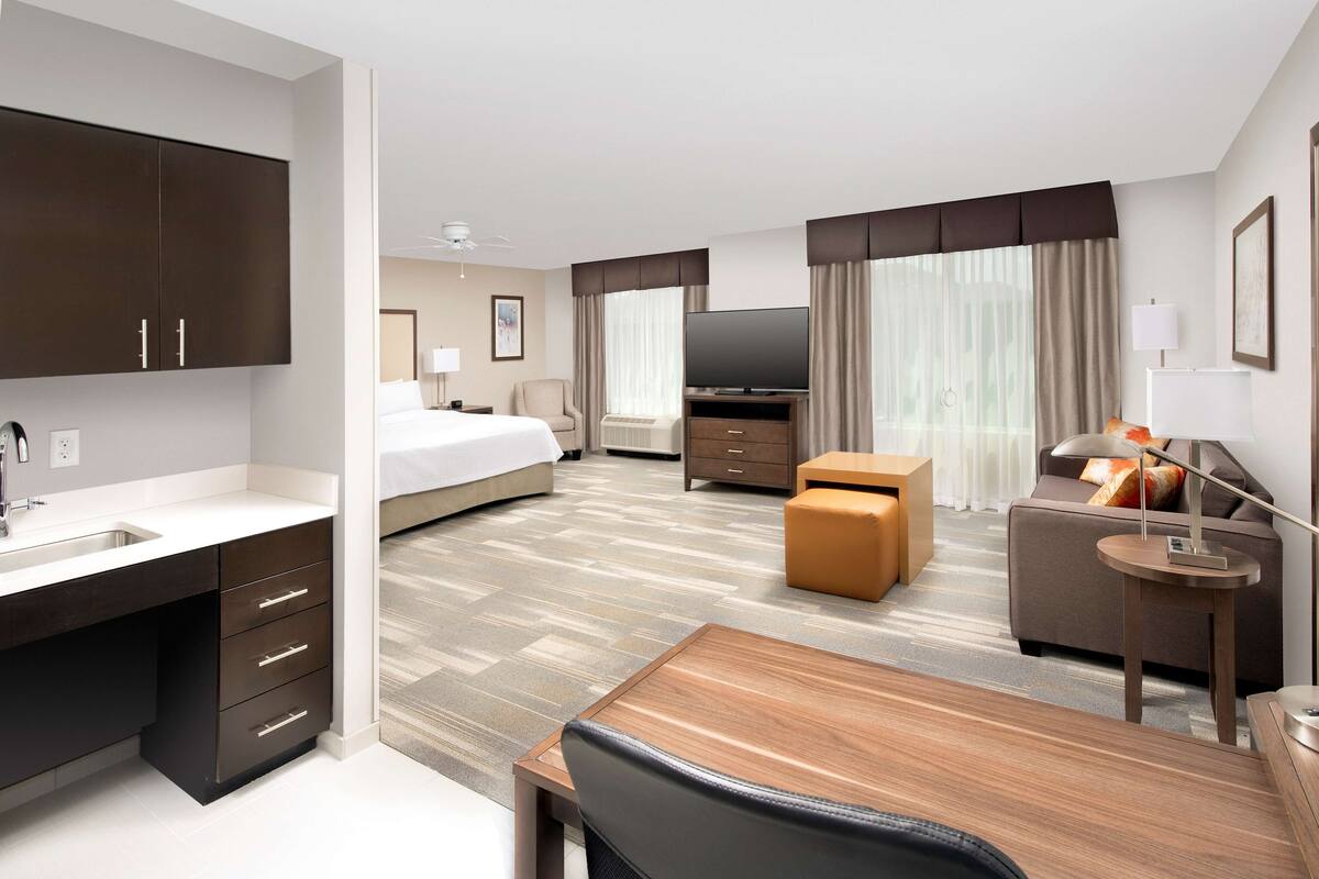 A hotel room with a bed, a desk, a sofa, a TV, and a bathroom.