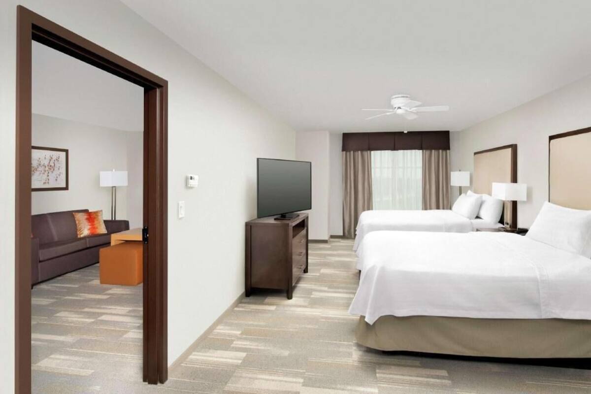 A hotel room with a bed, a TV, a sofa, and a desk.