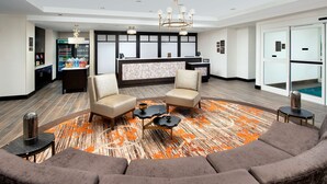 A modern lobby with a reception desk, seating area, and a minibar. - Homewood Suites by Hilton Kansas City Speedway (Kansas City)