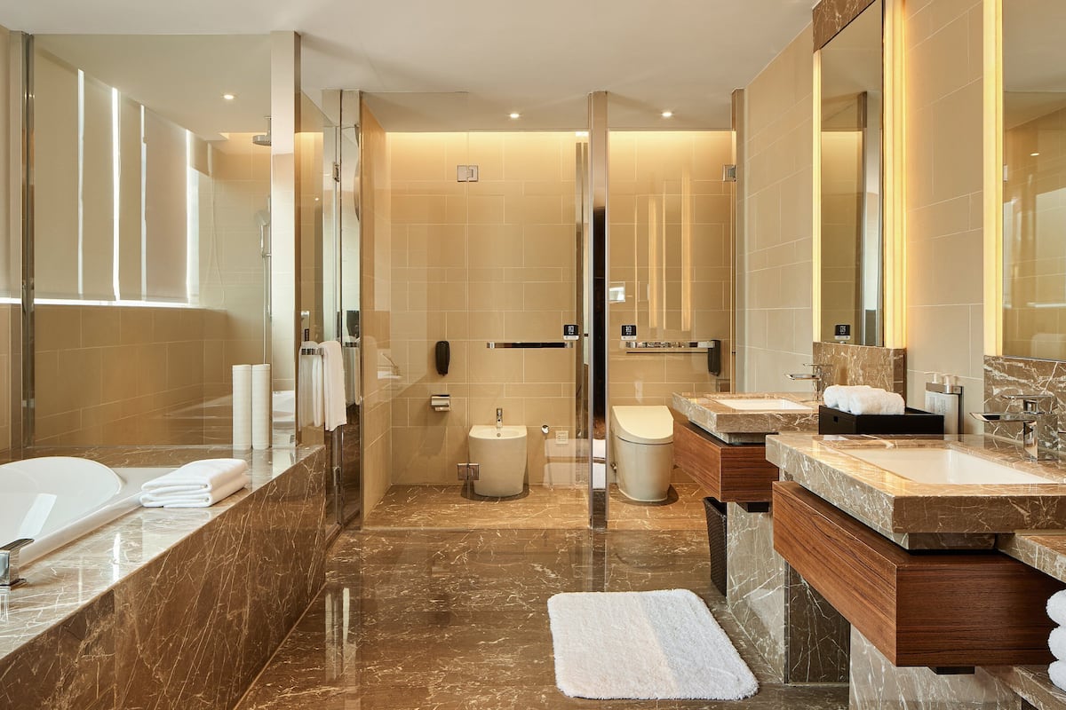 Une salle de bain moderne dotée d’une grande baignoire, d’une douche séparée et d’un meuble-lavabo avec un évier et un miroir.