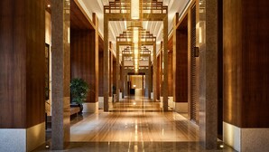 A spacious, modern hotel lobby with a central chandelier, wooden columns, and a polished marble floor. - HUALUXE Ningbo Harbor City by IHG (Ningbo)