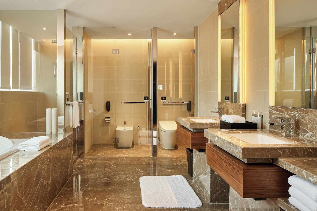 A modern bathroom with a large bathtub, a separate shower area, and a vanity with a sink and mirror.