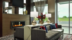 Un lobby moderno de hotel con chimenea, asientos cómodos y ventanas amplias que ofrecen vistas al exterior.