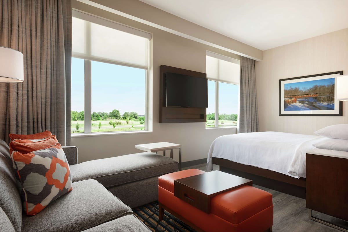 Une chambre d’hôtel avec un lit, un canapé, une petite table et un téléviseur.