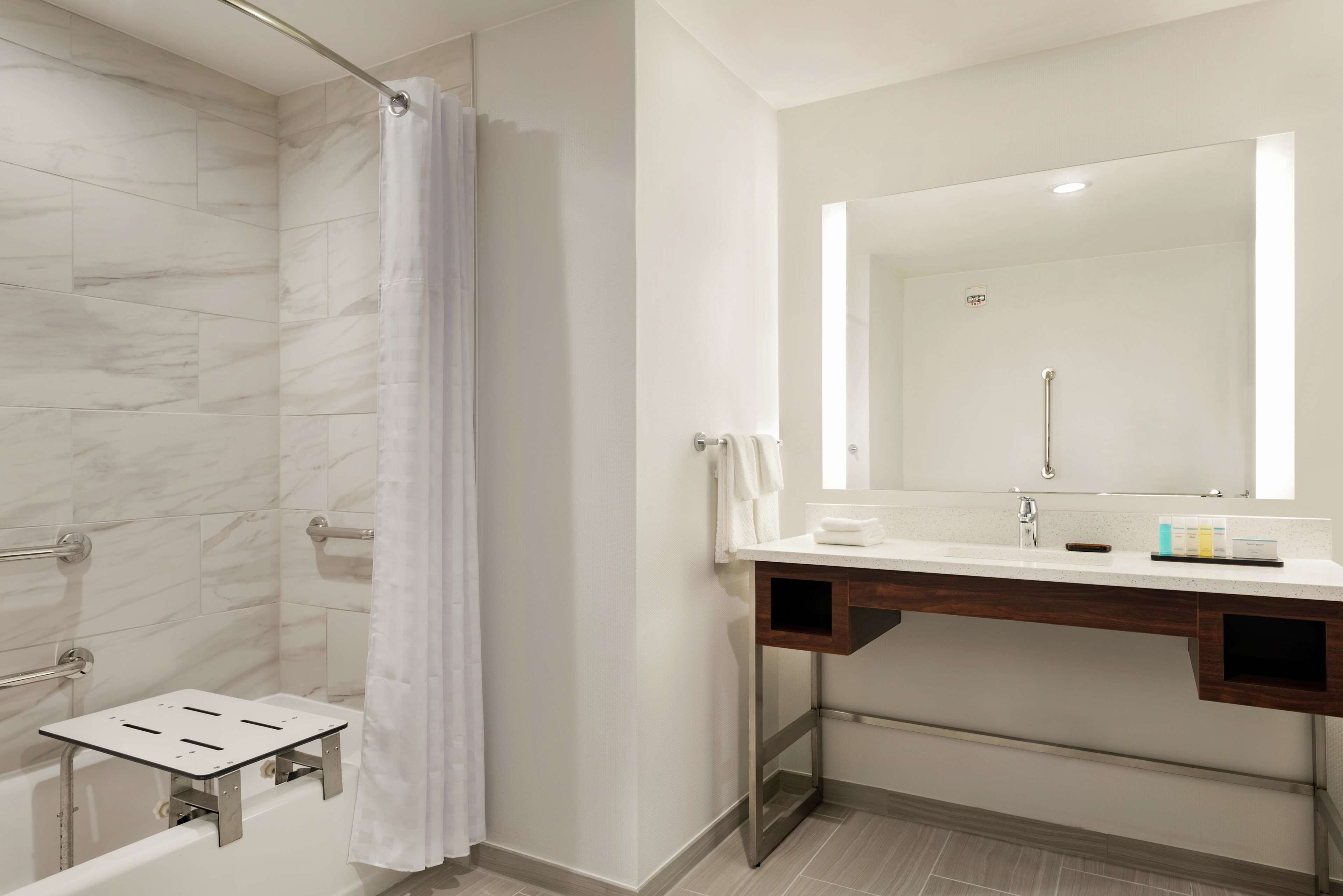 A modern bathroom with a shower, a vanity with a mirror, and a towel rack.